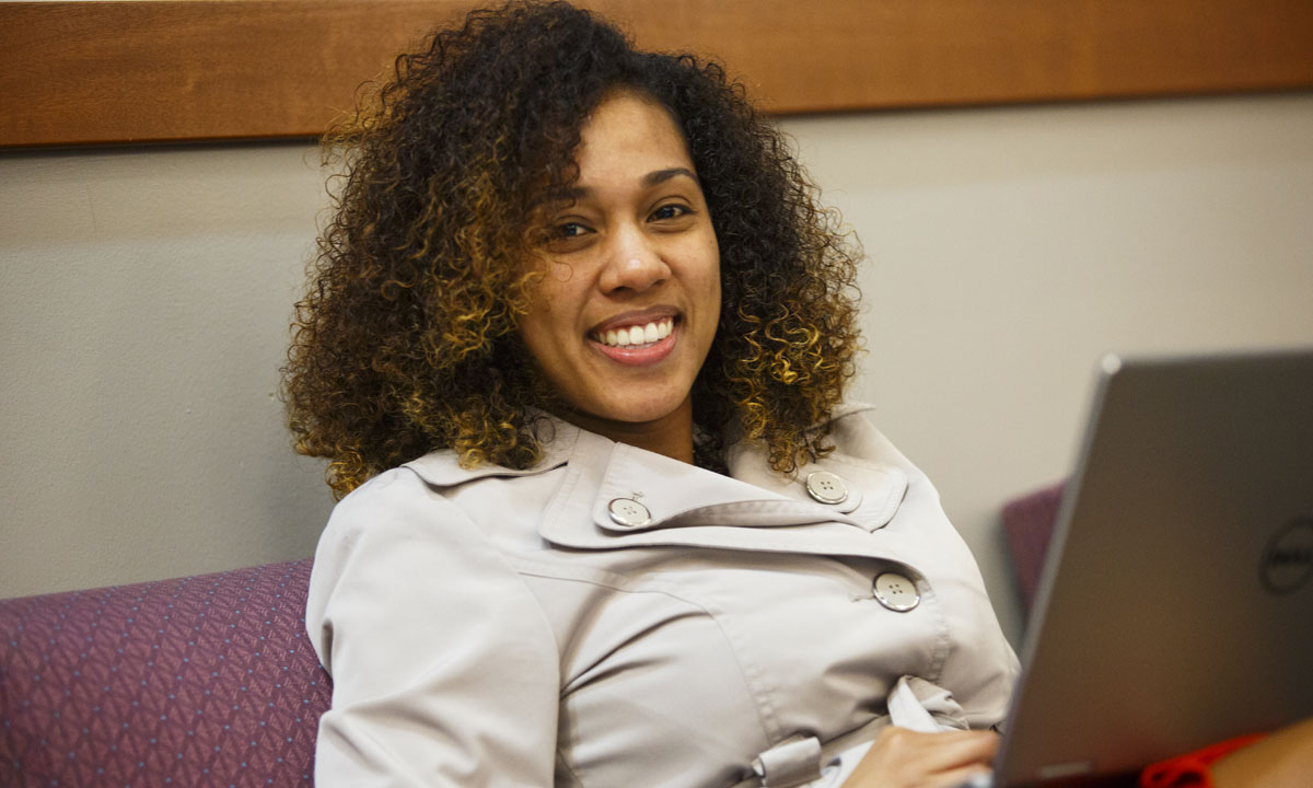 female student looking up from hera laptop smiling