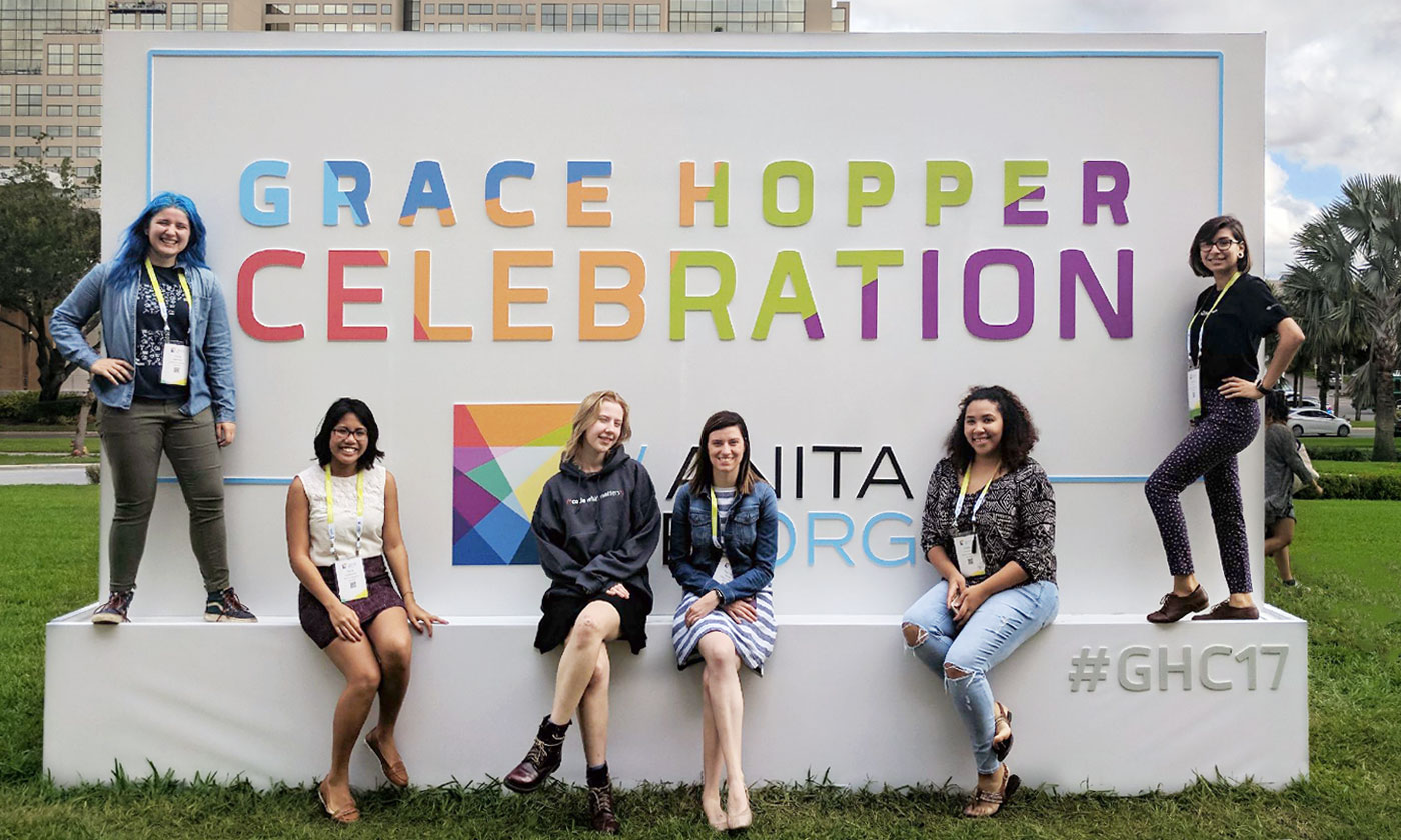 a few female students posing infront of sign